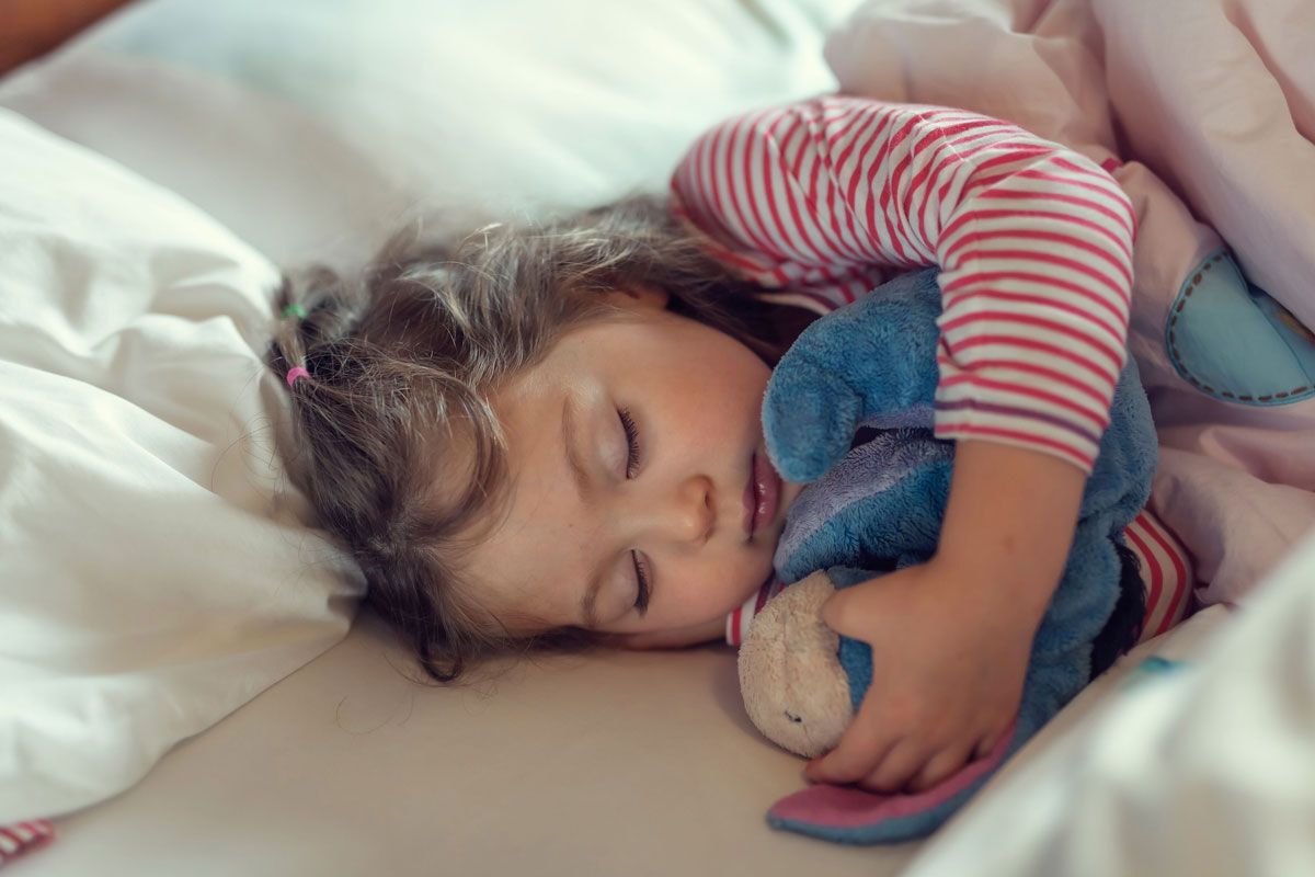 child holding stuffed toy while sleeping